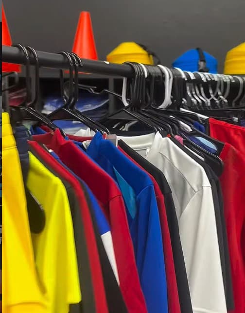 Racks of jerseys and training tops in yellow, red, blue and white at Xpress Sports